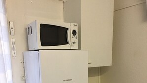 A compact kitchenette with a microwave, a small refrigerator, a drawer, and a vent. - PAVILLON T 2 RENOVE 4PERS VAUX SUR MER TERASSE PARKING PISCINE COLLEC COMM ETC (Vaux-sur-Mer)