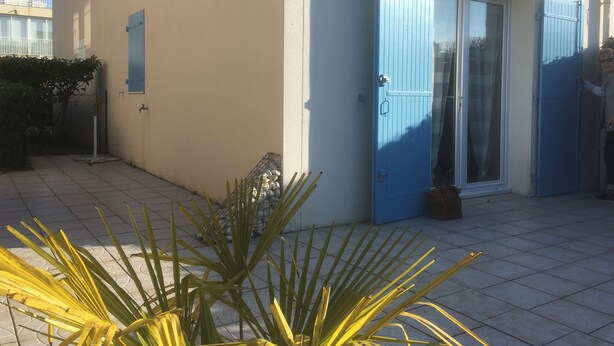 A house with a blue door, a white awning, and a tiled patio. - PAVILLON T 2 RENOVE 4PERS VAUX SUR MER TERASSE PARKING PISCINE COLLEC COMM ETC (Vaux-sur-Mer)