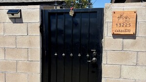 A black metal gate with a house-shaped plaque reading '13225 casita' on a beige brick wall.
