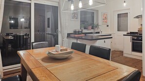 Un coin repas avec une table en bois, des chaises et un récipient contenant divers objets.