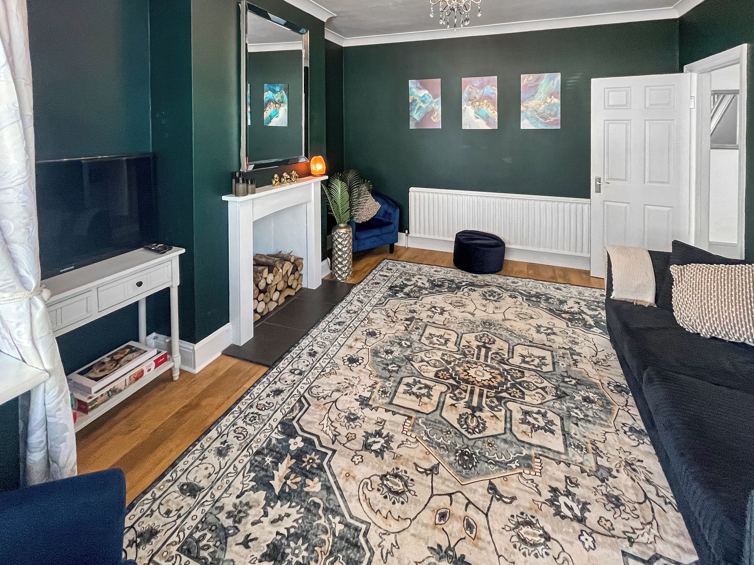 Un salon avec un téléviseur, une cheminée, un canapé et un tapis décoratif.