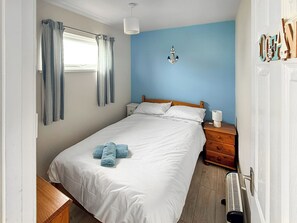 A bedroom with a bed, a nightstand, a lamp, and a window with curtains. - No 1 Hickling Chalet - UK51726 (California, near Great Yarmouth)