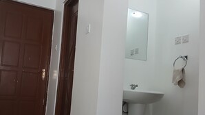 Een badkamer met een wit wastafelmeubel, een spiegel, een handdoekhouder en een deur.
