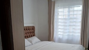 Een slaapkamer met een bed, gordijnen, een raam en een deur.