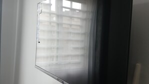 Een flatscreen-tv bevestigd aan een muur, met een raam op de achtergrond.