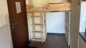 Eine kleine Küche mit Holzarbeitsplatte, einer kleinen Holzleiter und einem Kühlschrank.