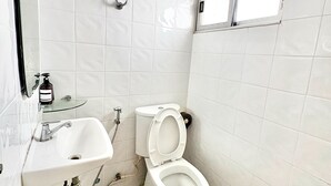 A bathroom with a toilet, sink, and window. - Prompt Inn Chareonkrung (Bangkok)