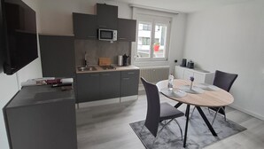 A modern kitchen with dark cabinets, a microwave, and a dining area with a round table and chairs.
