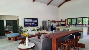 Una sala de estar moderna con una mesa de comedor de madera, sofás grises y un televisor montado en la pared.