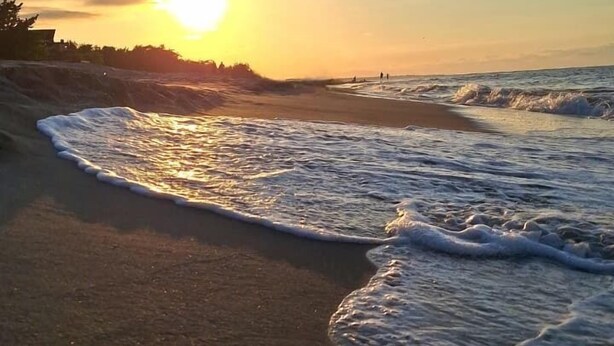 Una playa con olas y un atardecer.
