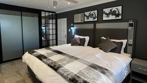 Une chambre à coucher moderne avec un grand lit, un ventilateur de plafond et des œuvres d’art accrochées aux murs.