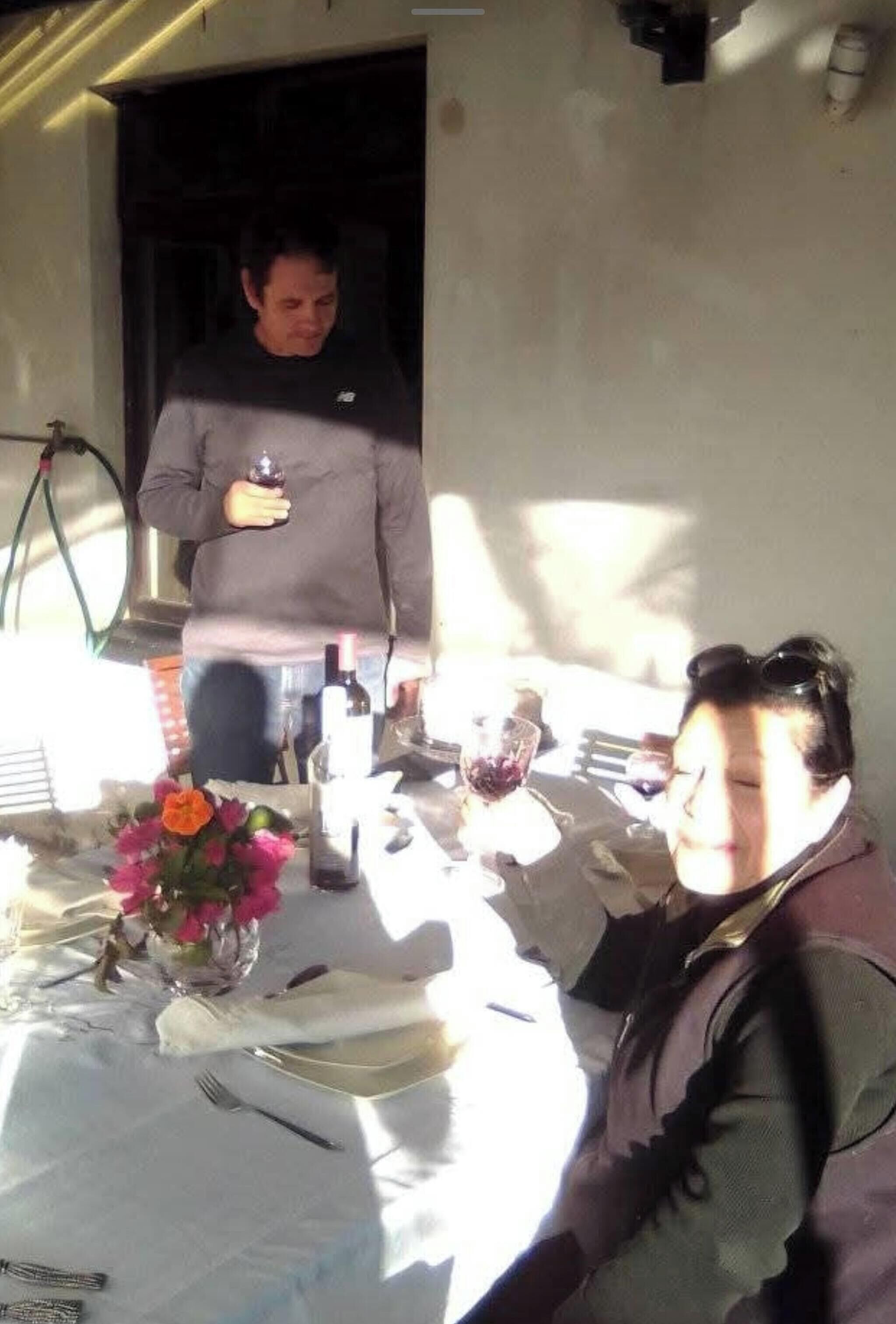 A dining table set with plates, cutlery, and a bottle of wine.