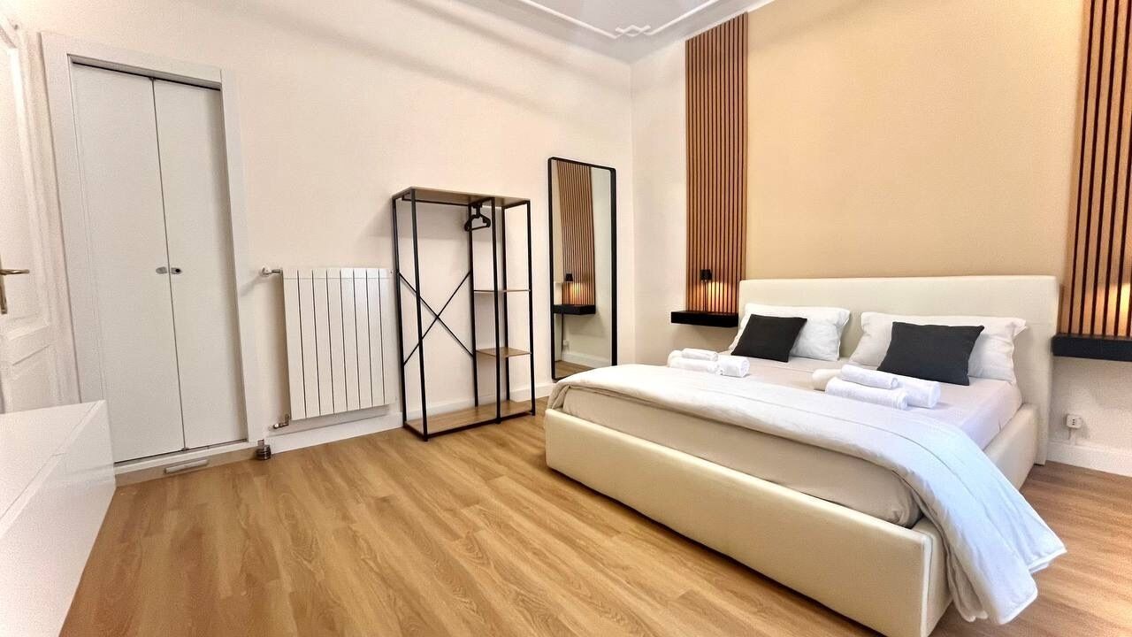 Une chambre à coucher avec un lit, un miroir, un radiateur et une armoire.