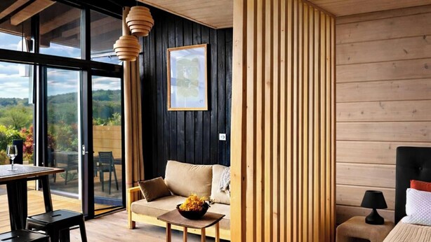 A modern interior with a sofa, dining table, and a bed with a black headboard.