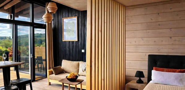 A modern interior with a sofa, dining table, and a bed with a black headboard.