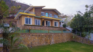 Una casa de dos pisos con fachada de piedra, un césped verde y un balcón.