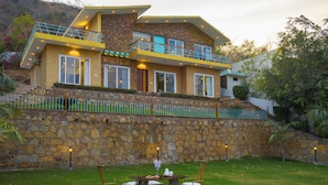 Una casa moderna con fachada de piedra, un balcón y un césped bien cuidado.