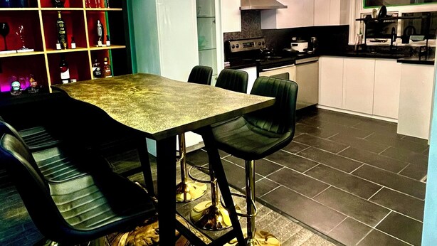 A modern kitchen with a dining area, featuring a table with chairs, a built-in oven, and a countertop with a sink. - The private room in bungalow in Richmond Hill perfect for a relaxing getaway (Richmond Hill)