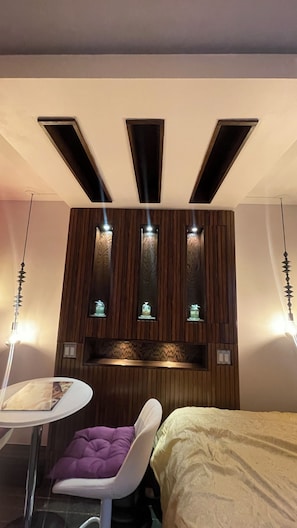 Habitación de hotel con cama, una mesita con una silla y un panel decorativo con luces.