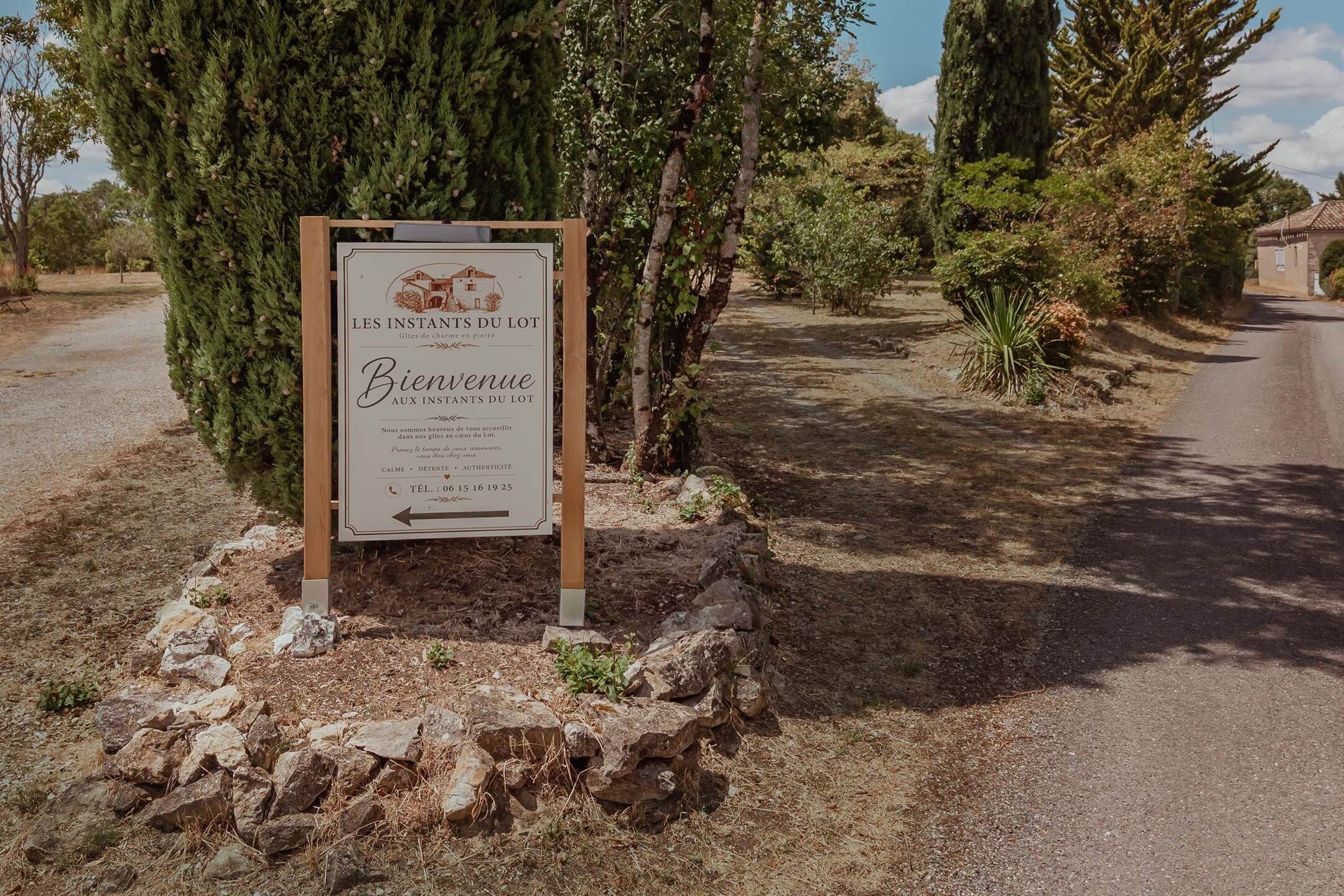 A welcome sign for 'LES INSTANTS DU LOT' with contact information.