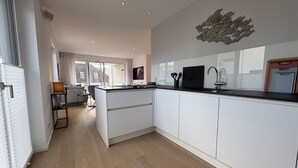 A modern kitchen with white cabinets, a black countertop, and a unique wall decoration. - Strandwiese - Baltic Sea Happiness - "Baltic Sea Happiness"... The sound of the sea included! (Dahme)