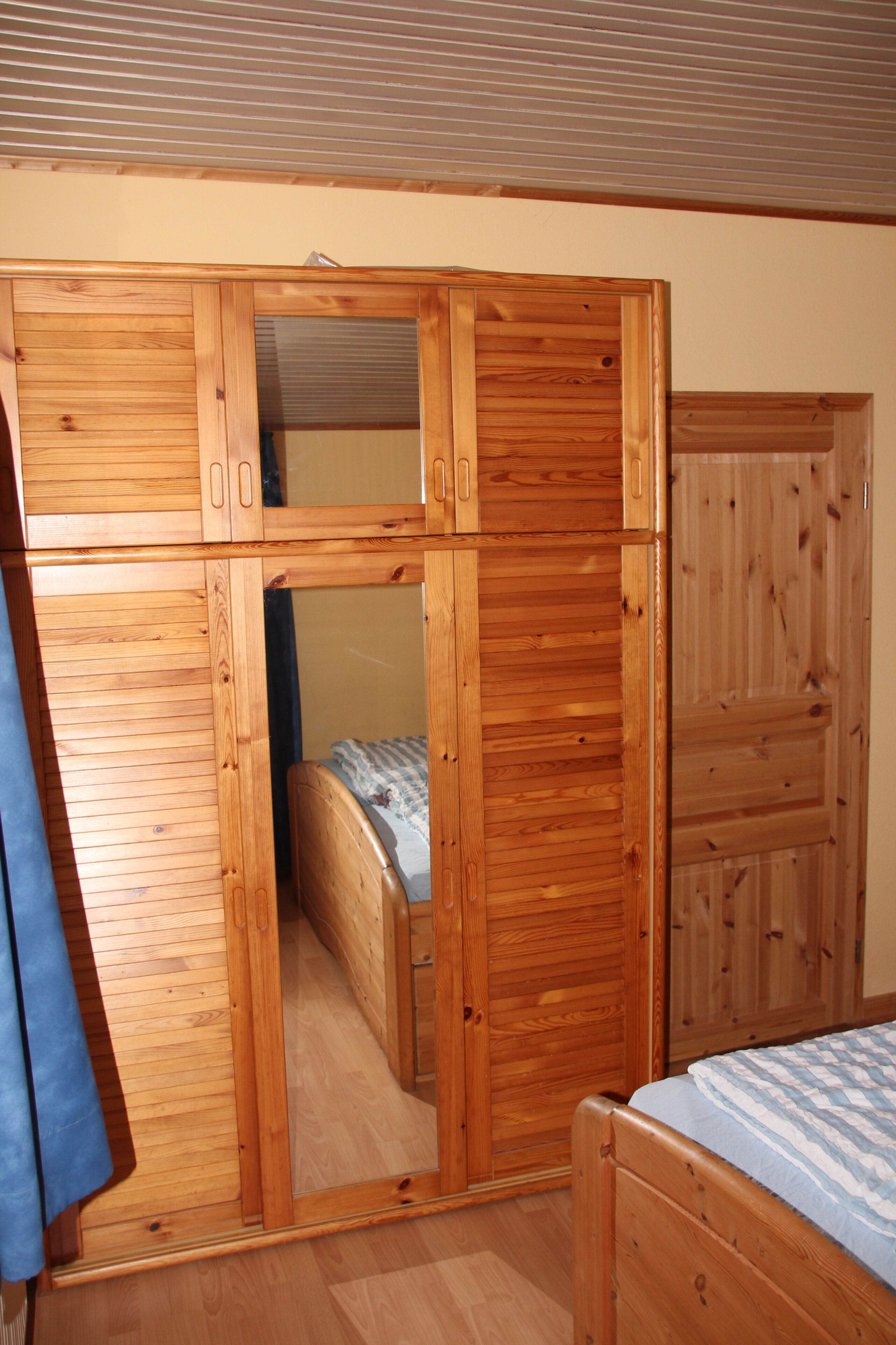 Une chambre à coucher avec une armoire en bois, un lit et un miroir.