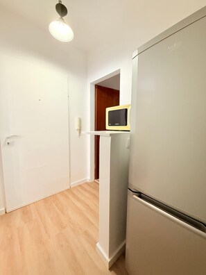 Eine Küche mit Kühlschrank, Mikrowelle und einer Holztür.
