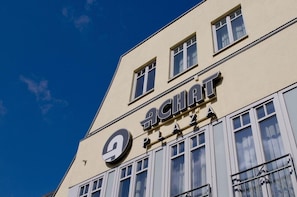 Un edificio con un cartel que dice 'ACHAT PLAZA' y un logotipo circular sobre el cartel.