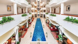 A hotel atrium with a central pool, multiple floors, and indoor plants. - AP Oriental Beach - Adults Only (Portimão)