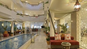 A hotel lobby with a pool, seating area, and decorative plants. - AP Oriental Beach - Adults Only (Portimão)