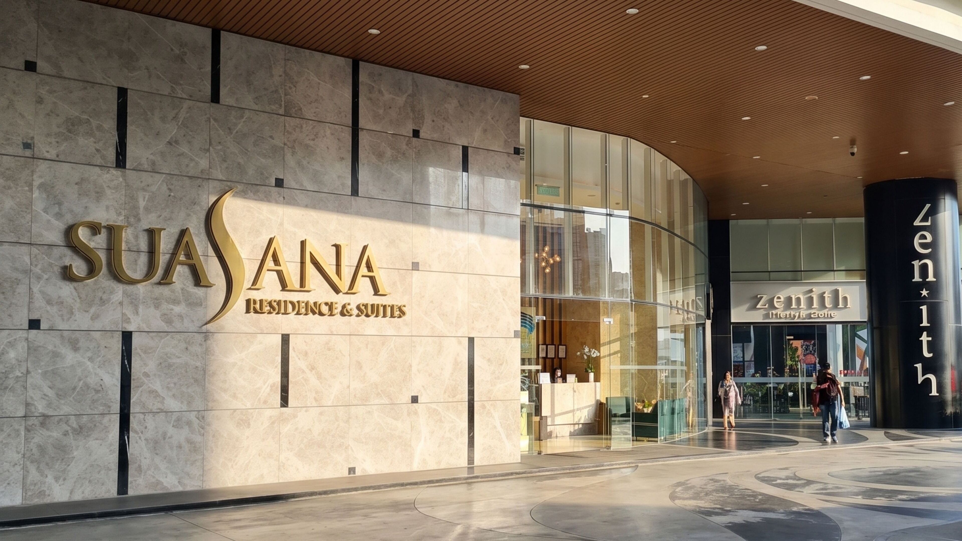 A modern building with a large sign for 'SUASANA RESIDENCE & SUITES' and a glass entrance.