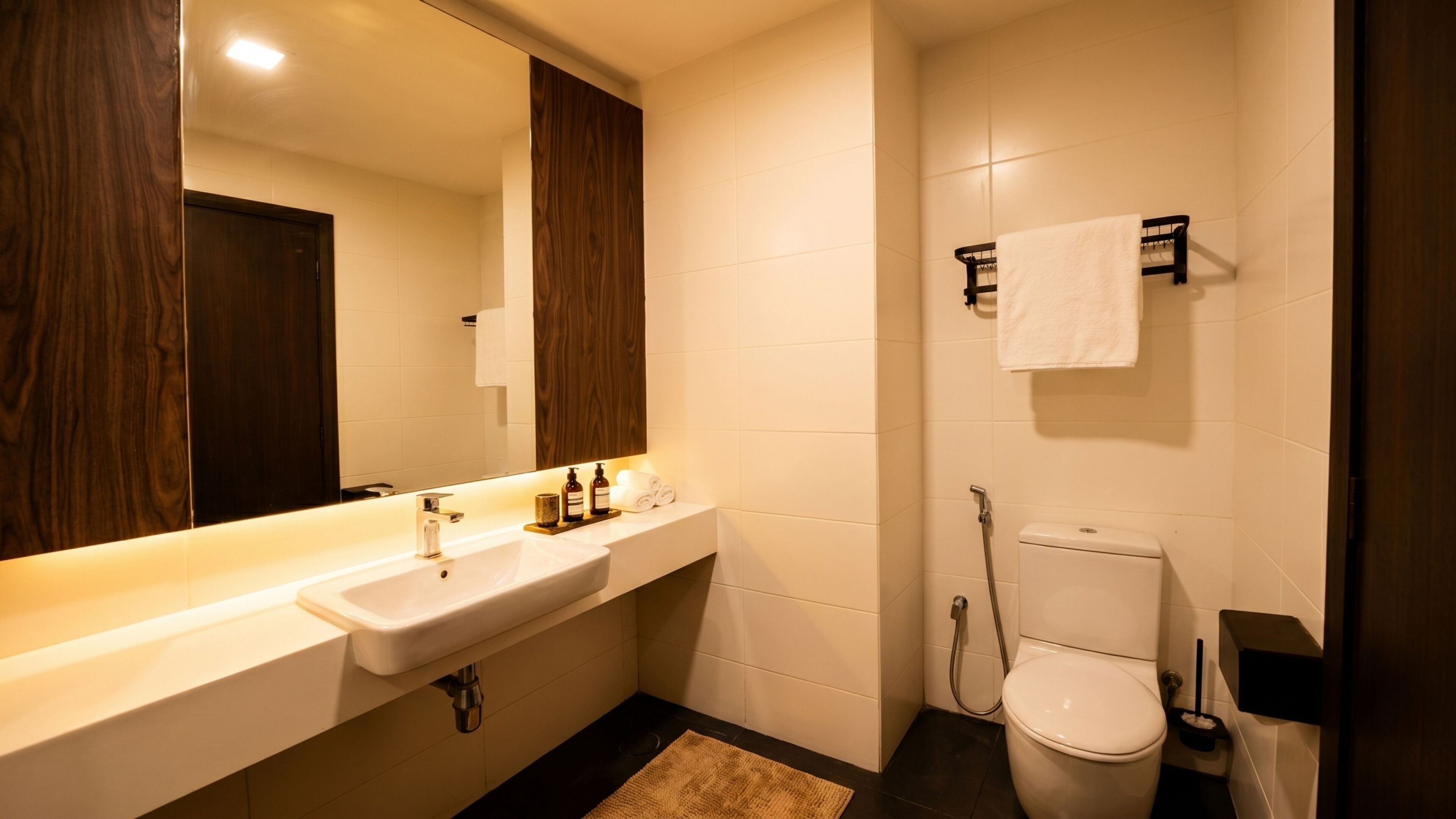 Un baño moderno con un espejo grande, un lavamanos, un inodoro y una ducha.