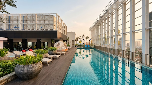 A rooftop pool with lounge chairs, potted plants, and a view of the cityscape. - Suasana JB Central by TPL (Johor Bahru)