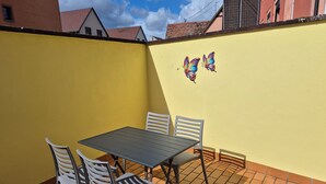 Un patio con tavolo e sedie, un muro giallo e due decorazioni a forma di farfalla.
