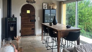 Ein gemütlicher Wohnbereich mit einem Holzesstisch, schwarzen Stühlen, einem Globus und einem Koffer.
