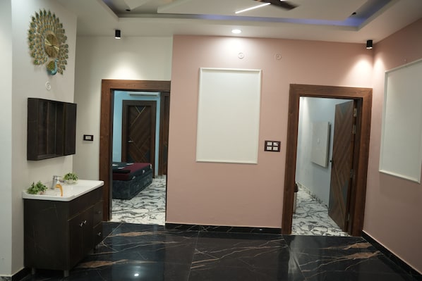 Une salle de bain moderne avec un sol en marbre foncé, un lavabo blanc et un élément décoratif mural.