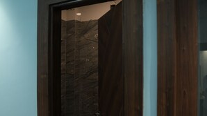Eine Holztür, die in einen Raum mit Fliesenboden und einer sichtbaren Klimaanlage darüber führt.