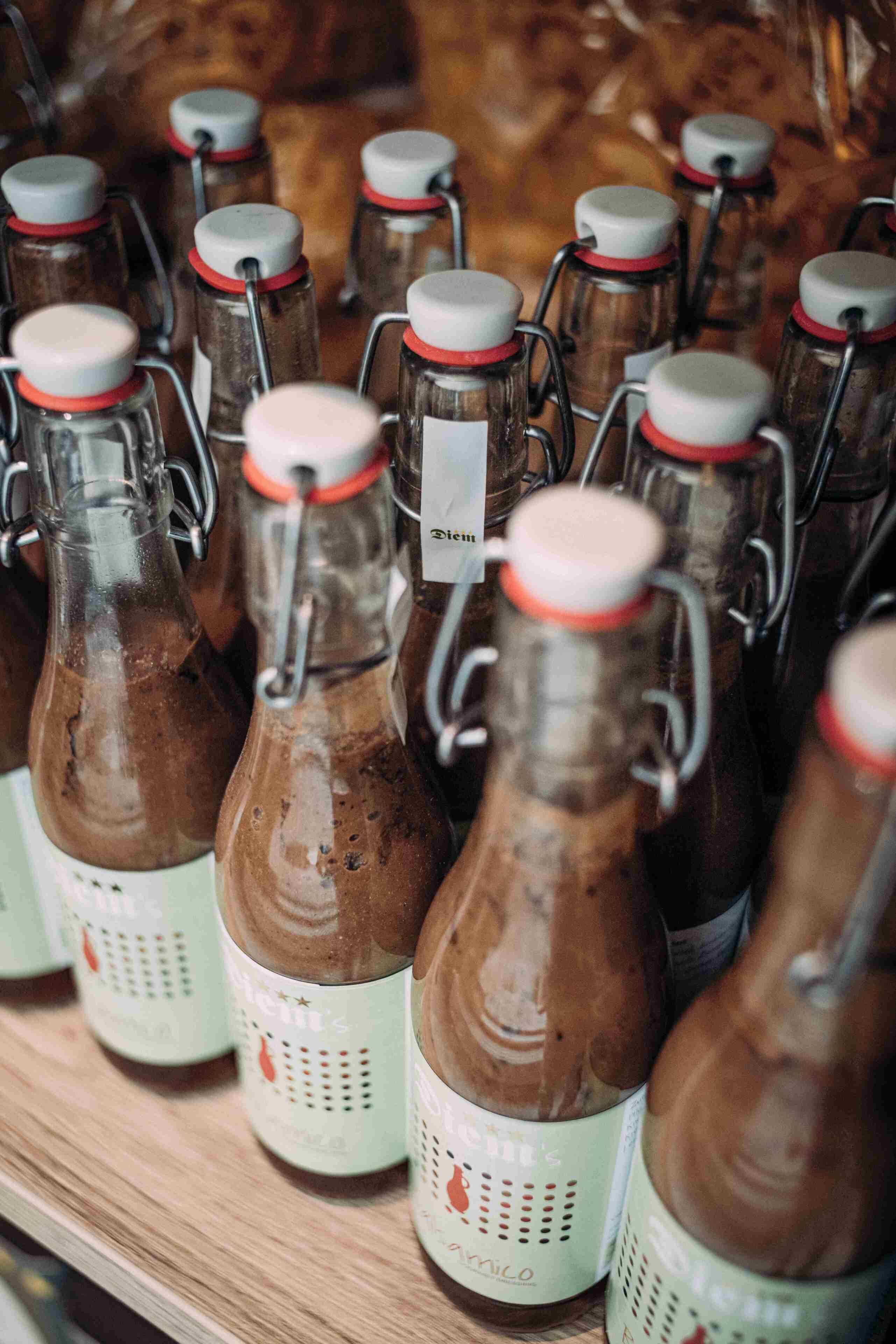 Varias botellas de vidrio con cierres metálicos y etiquetas blancas, presumiblemente conteniendo una bebida.