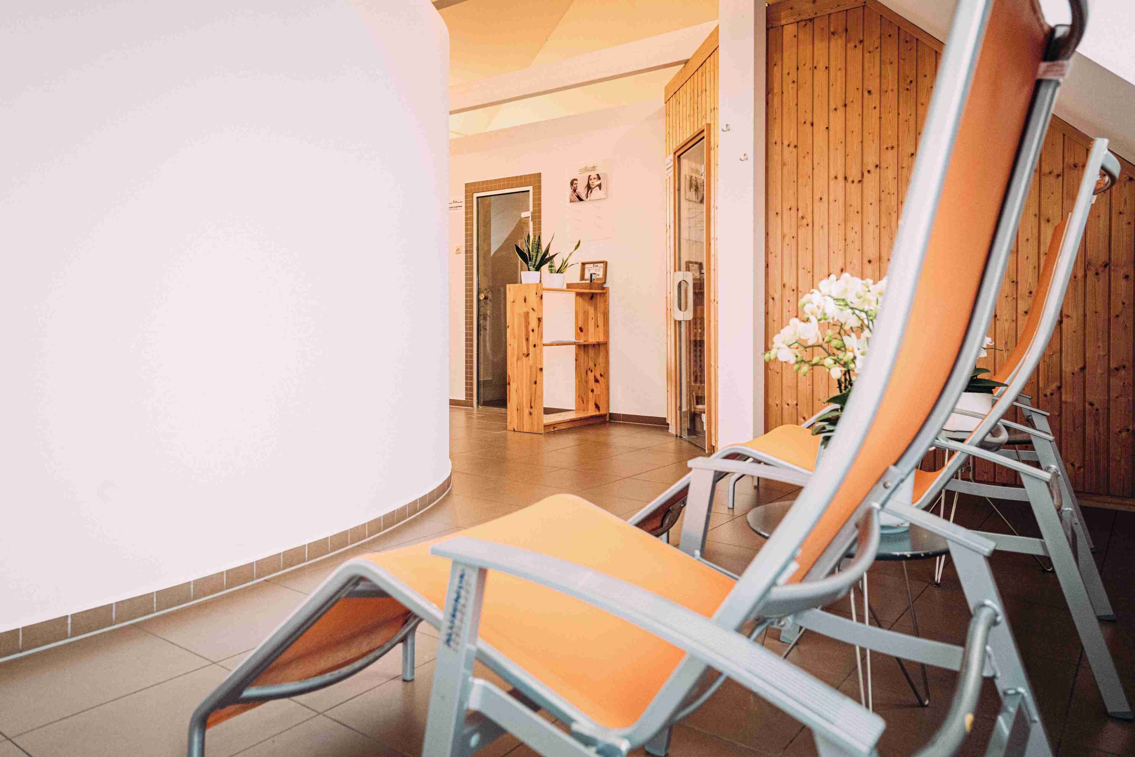 A room with a curved wall, a wooden reception desk, and a seating area with chairs.