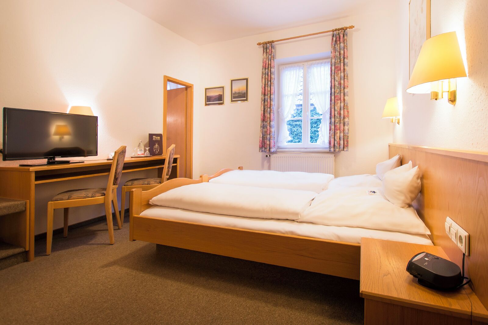 Une chambre d’hôtel équipée d’un lit, d’un bureau, d’une chaise, d’une télévision et d’une fenêtre avec des rideaux.