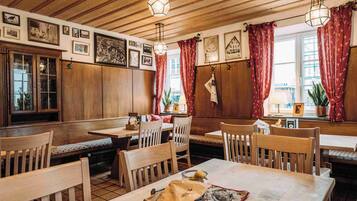 Un restaurante acogedor con mobiliario de madera, lámparas colgantes y cuadros en las paredes.