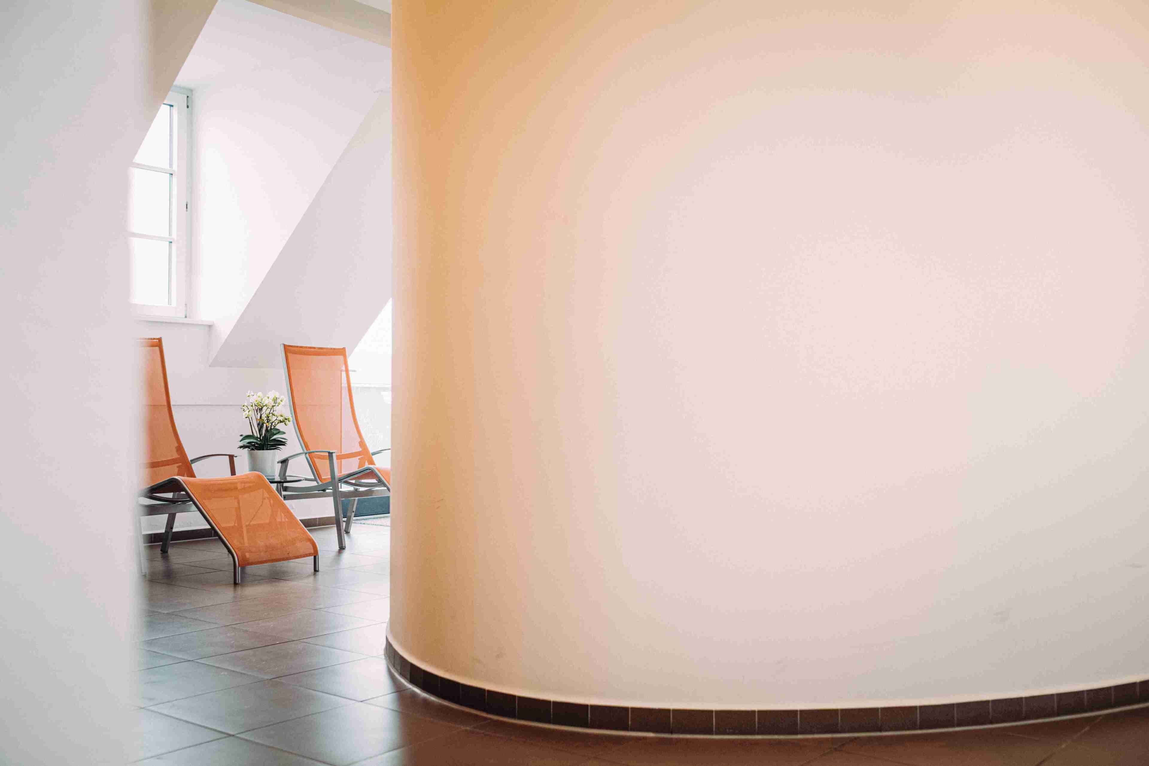 A spacious interior with a high ceiling, a curved wall, and a seating area with chairs.