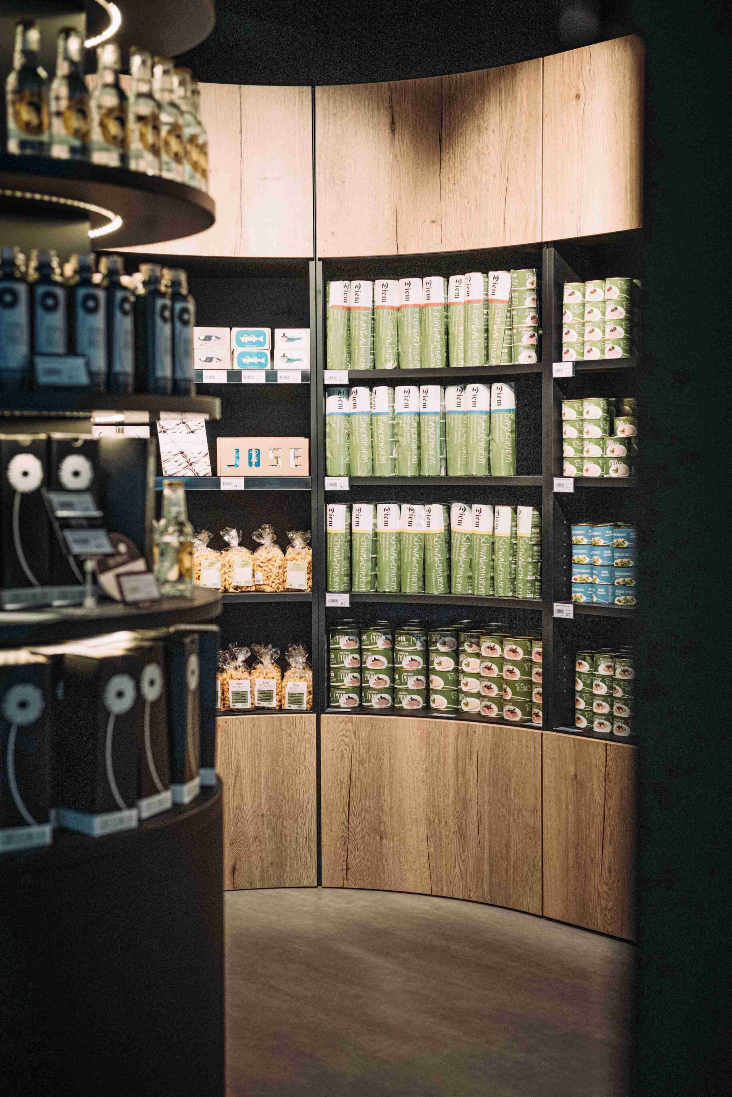 A store interior with shelves stocked with products, a counter with a display, and a wooden wall.