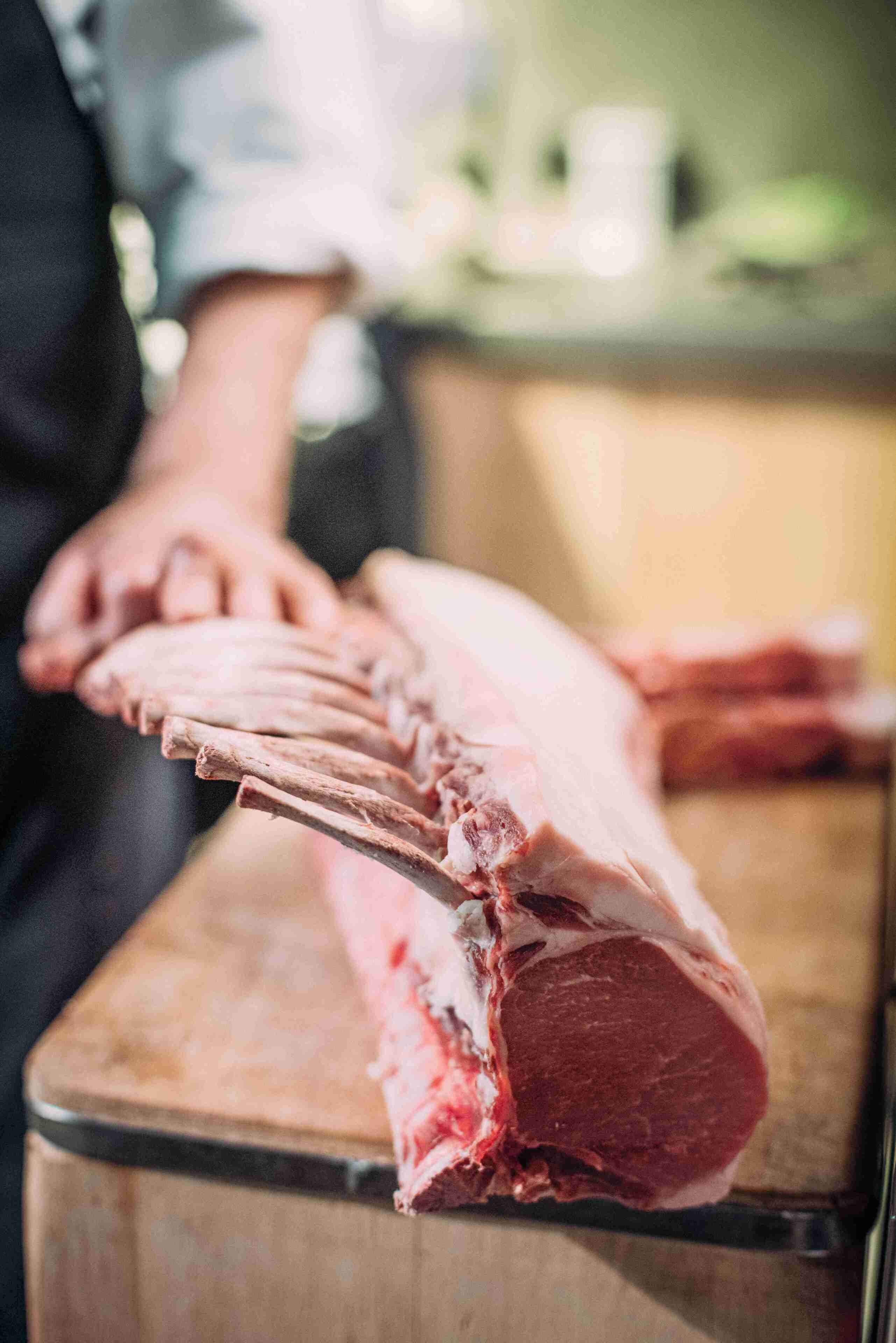 A large piece of raw meat on a wooden cutting board.