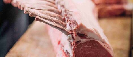 A large piece of raw meat on a wooden cutting board.