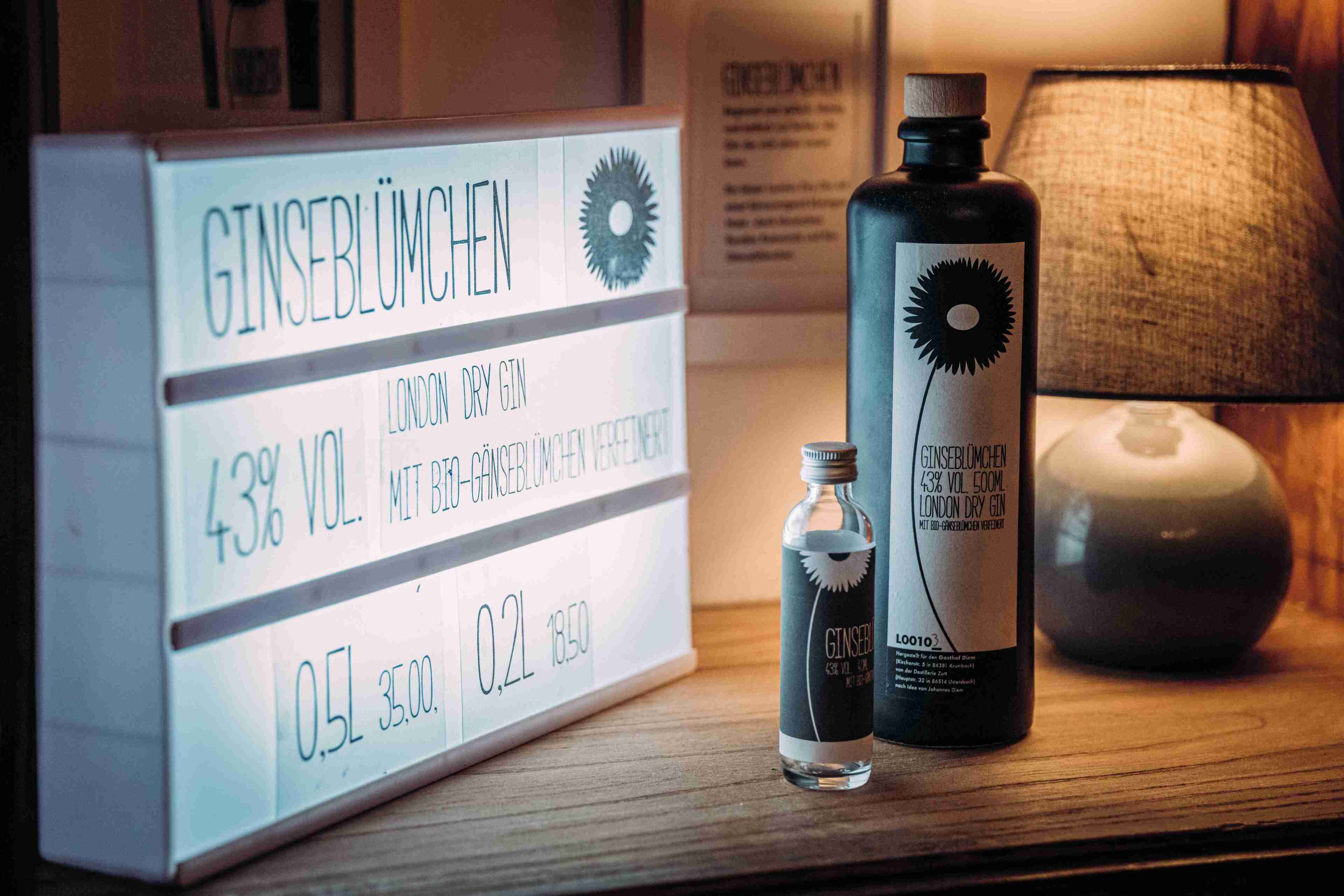 Una botella de ginebra London Dry, una botella pequeña de ginebra y un cartel con los precios de la ginebra.