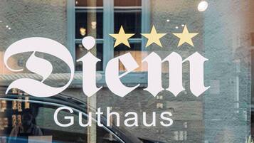 Une fenêtre sur laquelle on peut lire le texte « Diem Guthhaus » et au-dessus, trois étoiles.
