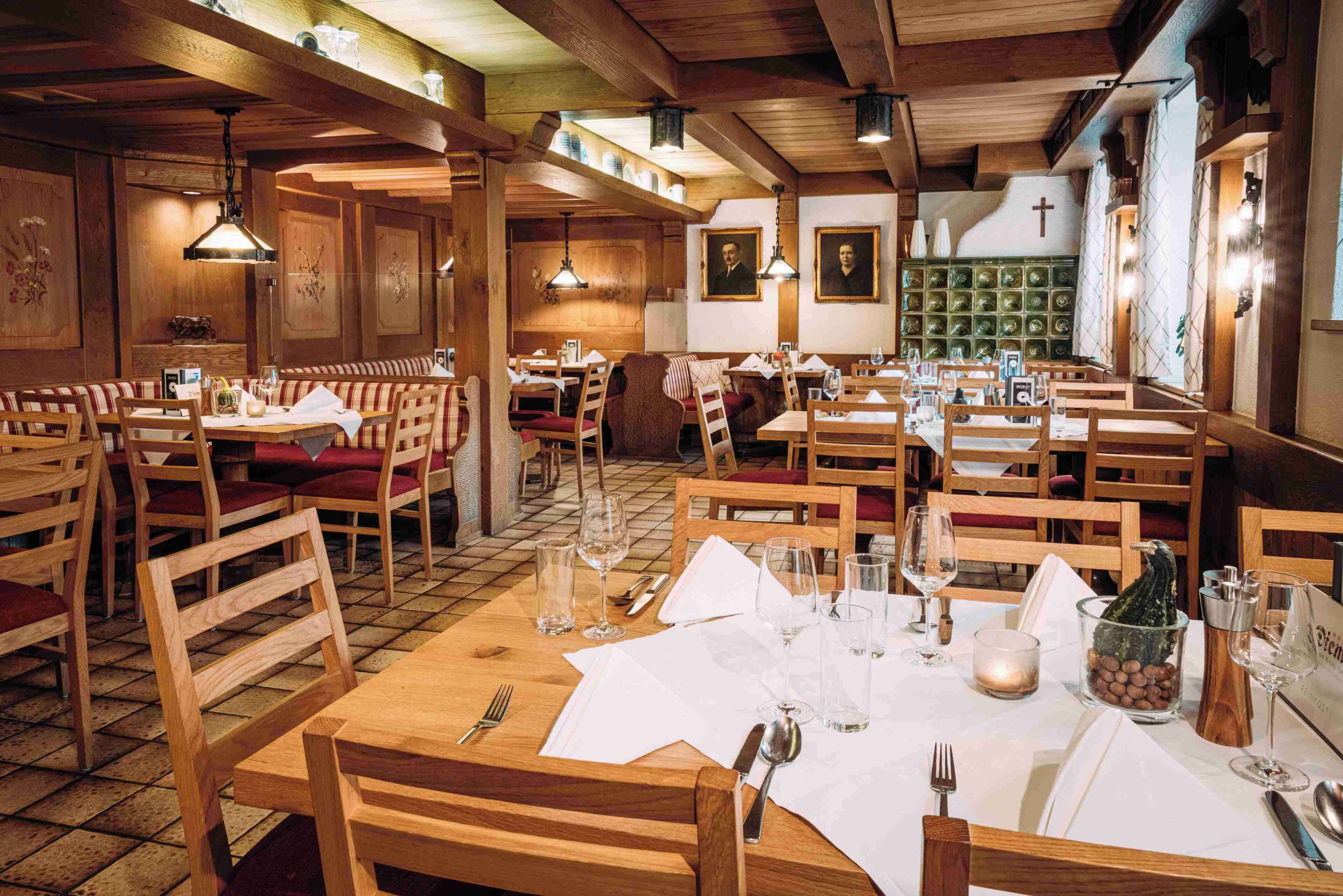 A restaurant with wooden tables and benches, framed pictures on the walls, and a tiled floor.