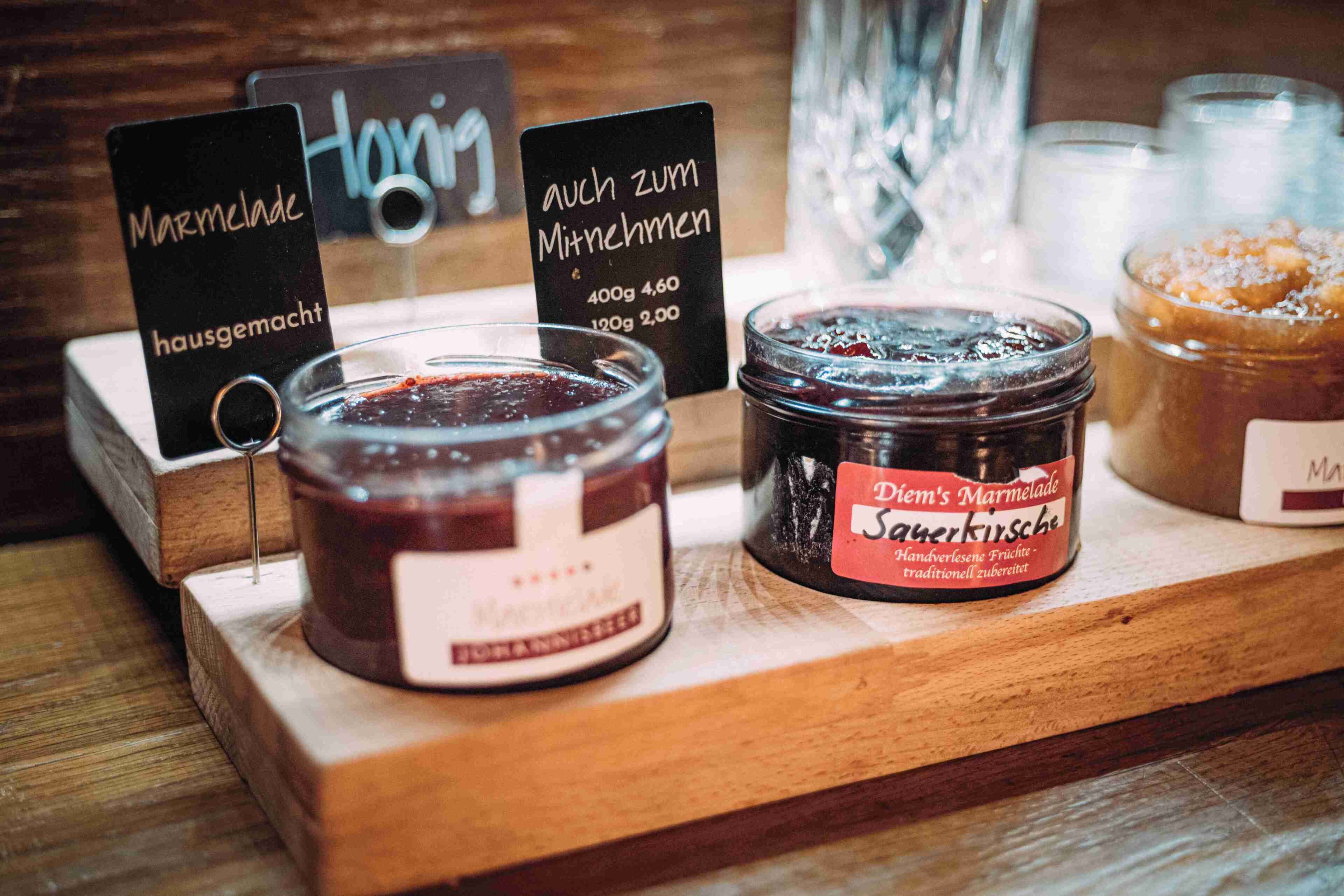 Gleaming Marmeladen- und Honiggläser auf einer Holzpräsentation mit Preisschildern.