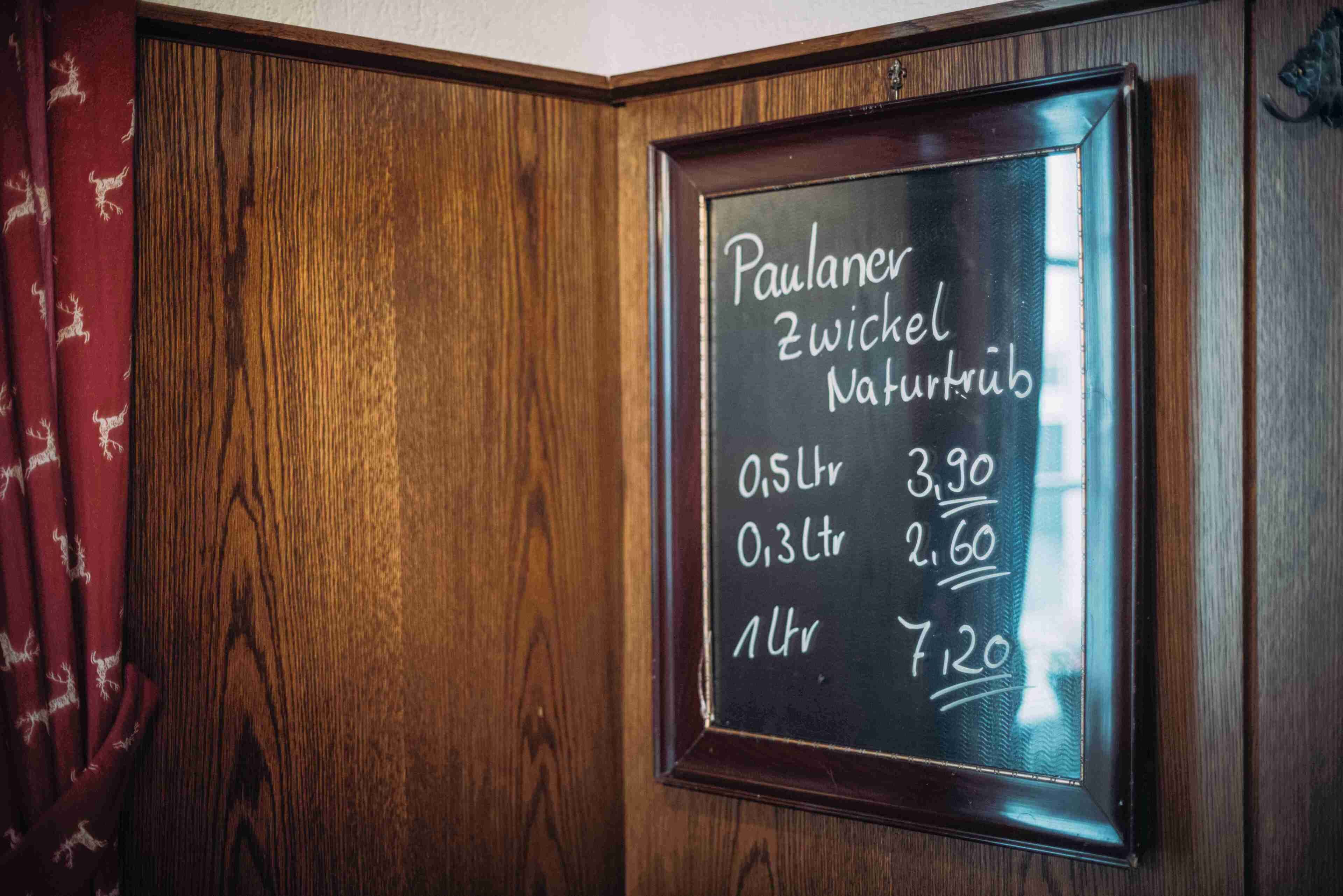 Eine gerahmte Kreidetafel mit Preisen für Paulaner Zwickel Naturtrüb Bier.